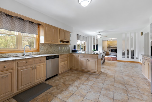 kitchen featuring ceiling fan, sink, kitchen peninsula, dishwasher, and a fireplace