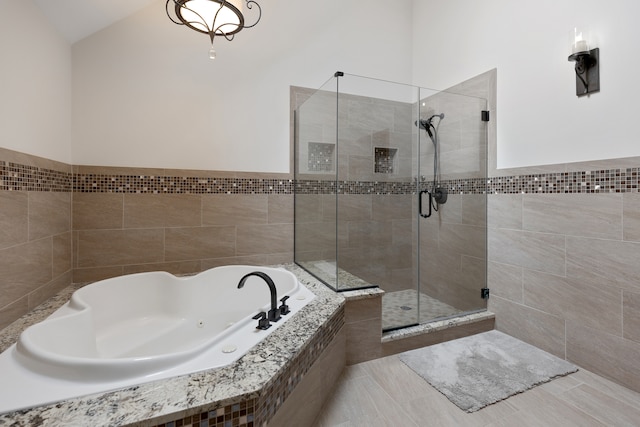 bathroom with shower with separate bathtub, lofted ceiling, and tile patterned flooring