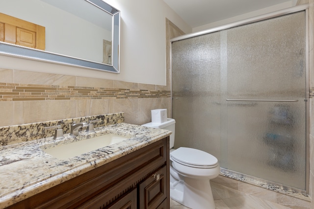 bathroom with vanity, a shower with shower door, tile patterned floors, tile walls, and toilet