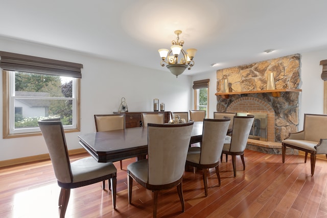 dining space featuring a healthy amount of sunlight, an inviting chandelier, hardwood / wood-style flooring, and a fireplace