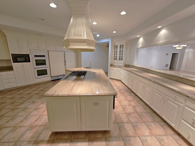 kitchen with sink, stainless steel gas stovetop, white cabinetry, a kitchen island, and double oven