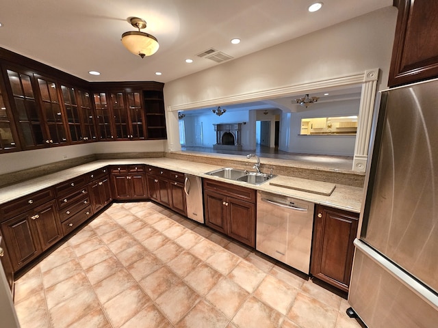 kitchen with light stone counters, appliances with stainless steel finishes, dark brown cabinetry, and sink