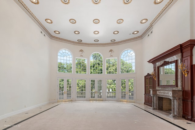 unfurnished living room with crown molding, a high ceiling, a fireplace, and a wealth of natural light