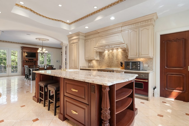 kitchen featuring hanging light fixtures, cream cabinetry, custom exhaust hood, and tasteful backsplash