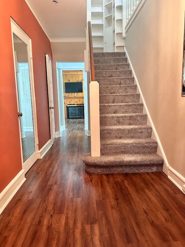 staircase featuring crown molding and hardwood / wood-style floors