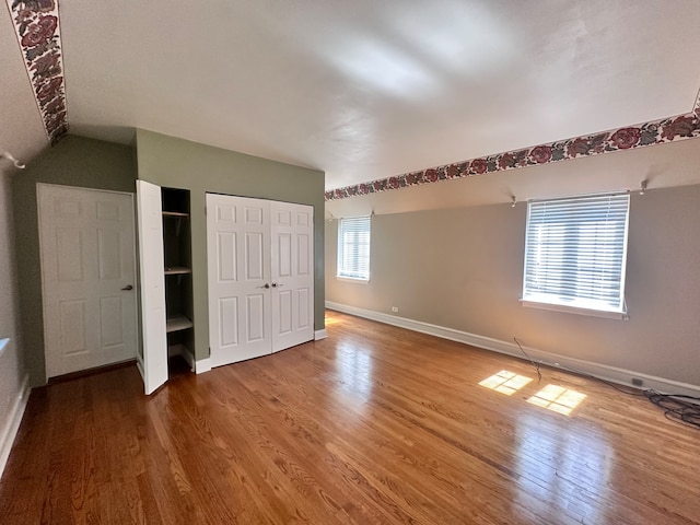 unfurnished bedroom featuring multiple windows and hardwood / wood-style flooring