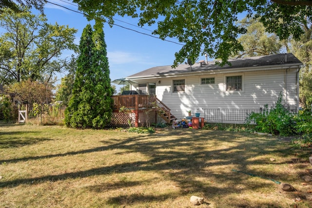 rear view of house with a lawn and a wooden deck