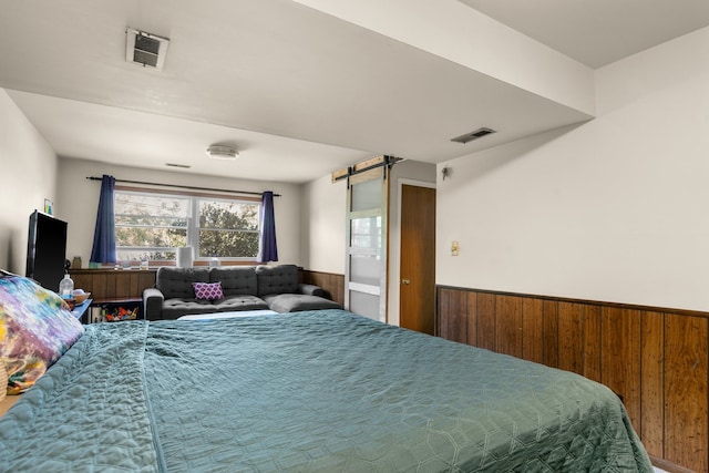 bedroom with a barn door and wood walls