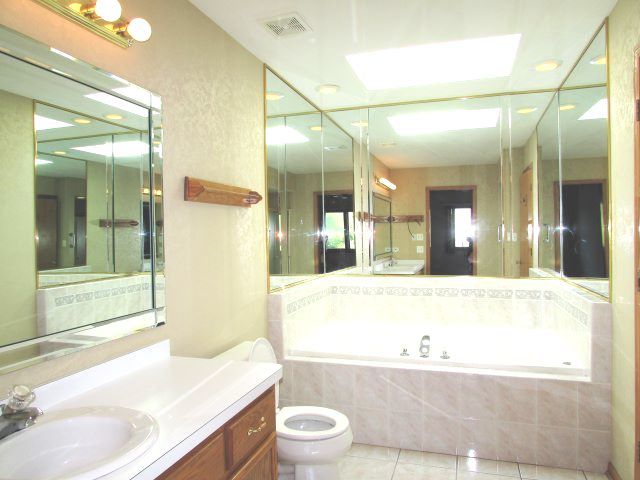 bathroom with tiled tub, tile patterned flooring, vanity, and toilet