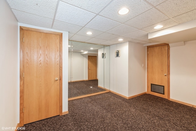 unfurnished room featuring a drop ceiling and dark colored carpet