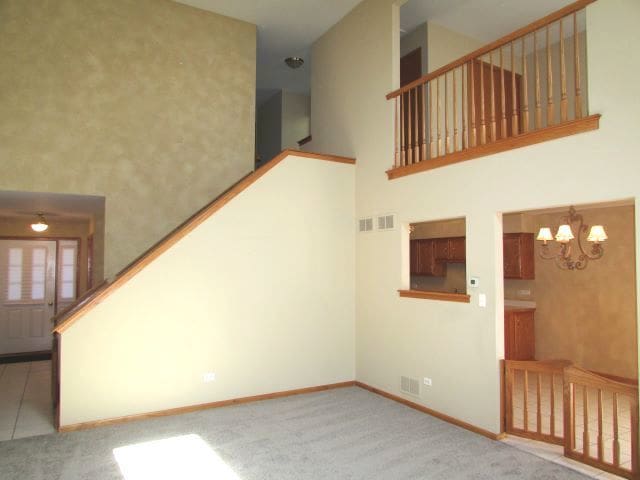 stairway featuring carpet flooring, an inviting chandelier, and a high ceiling