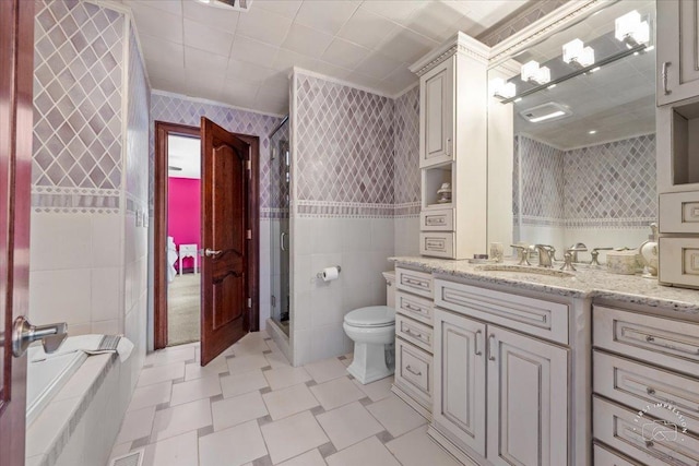 bathroom featuring toilet, vanity, tile walls, a shower stall, and wallpapered walls