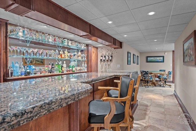 bar with a paneled ceiling, baseboards, bar area, and recessed lighting