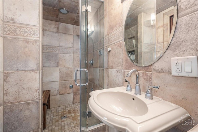 bathroom featuring decorative backsplash, a shower with shower door, and sink