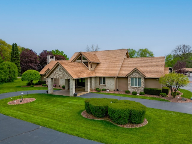 view of front of property featuring driveway, stone siding, and a front yard