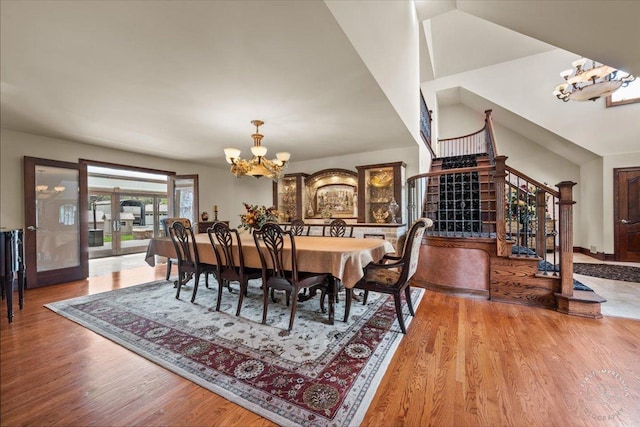 dining space with a chandelier, hardwood / wood-style floors, vaulted ceiling, and french doors