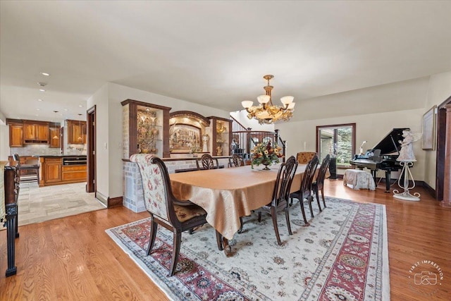 dining room featuring baseboards, an inviting chandelier, and light wood-style floors