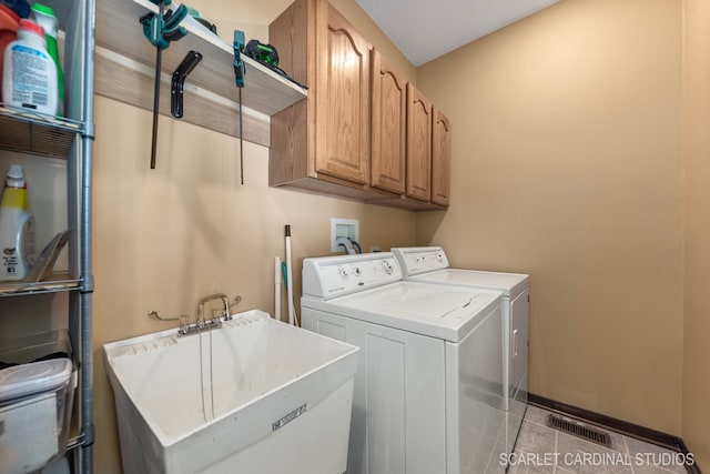 washroom featuring cabinets, sink, washing machine and dryer, and light tile patterned flooring