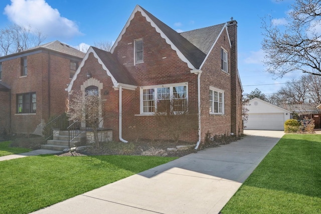 english style home with an outbuilding, a front lawn, and a garage