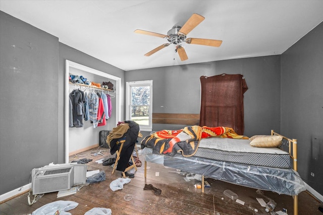 bedroom with hardwood / wood-style floors, ceiling fan, an AC wall unit, and a closet