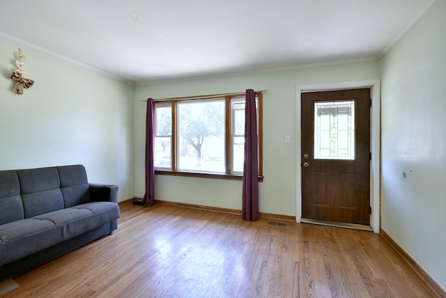 foyer featuring light wood-type flooring, ornamental molding, and a healthy amount of sunlight