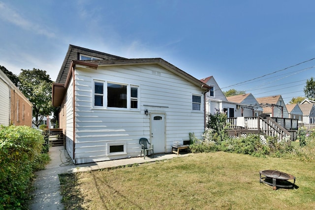 back of house featuring a deck, an outdoor fire pit, and a yard