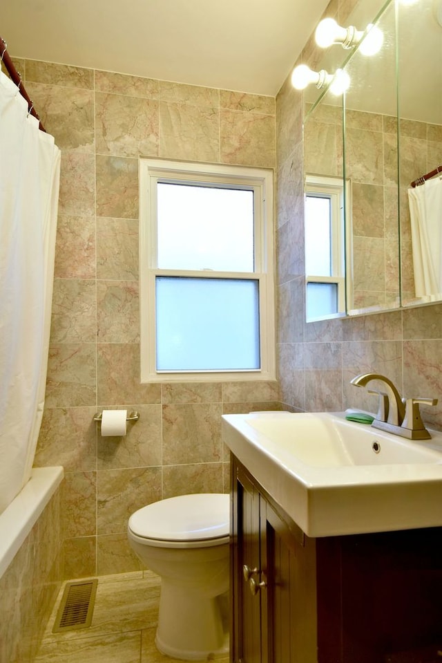 bathroom with tile walls, vanity, and toilet