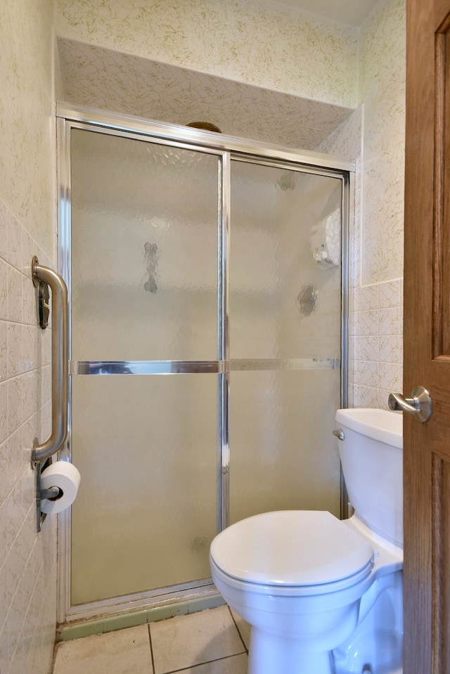 bathroom featuring tile walls, toilet, tile patterned floors, and a shower with shower door