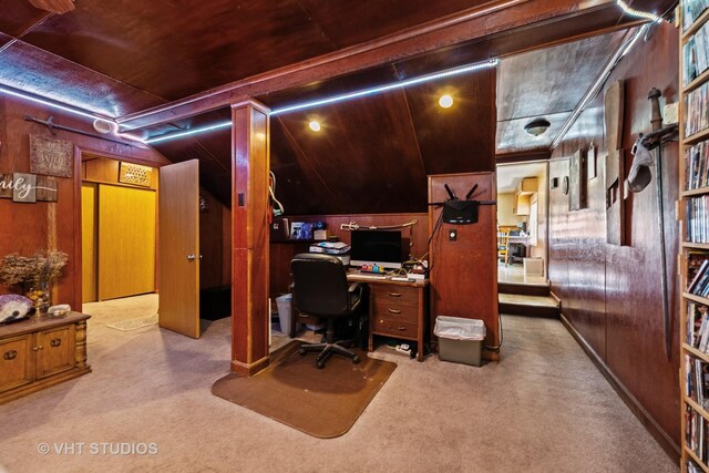 office area featuring vaulted ceiling, wooden walls, and carpet flooring