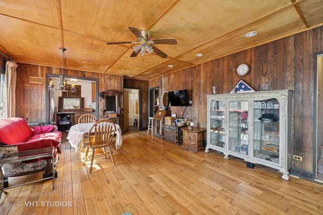 living room featuring visible vents, ceiling fan with notable chandelier, wood finished floors, wooden ceiling, and wood walls