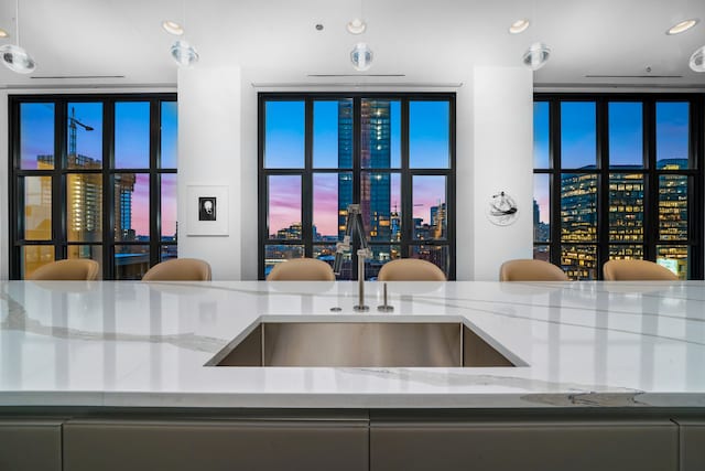 kitchen with light stone countertops, hanging light fixtures, and sink