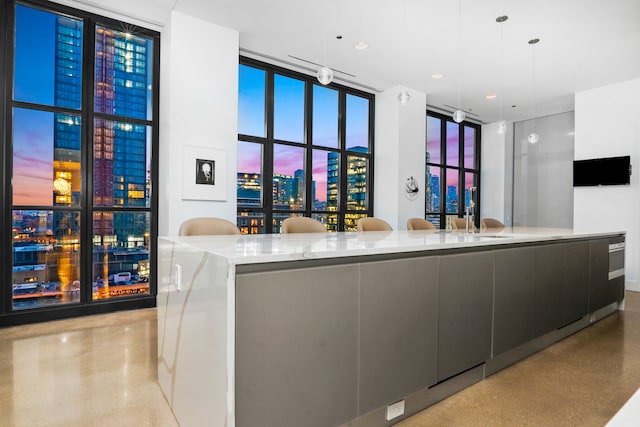 kitchen featuring a wall of windows, sink, pendant lighting, and a spacious island