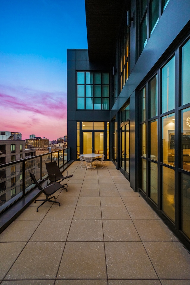 patio terrace at dusk featuring a balcony