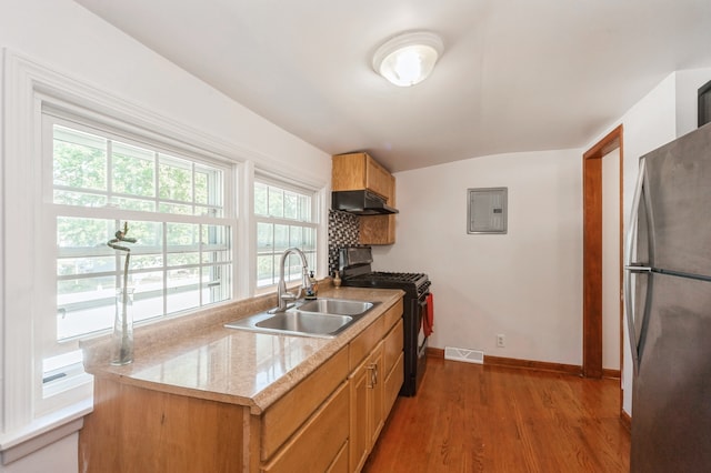 kitchen with electric panel, sink, black stove, dark hardwood / wood-style flooring, and stainless steel fridge