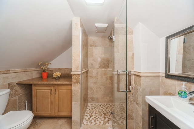 bathroom with vanity, toilet, walk in shower, tile walls, and tile patterned flooring