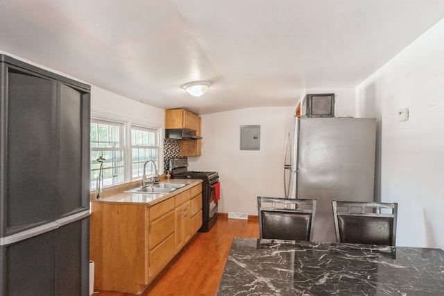 kitchen with electric panel, sink, stainless steel refrigerator, light hardwood / wood-style flooring, and black gas range