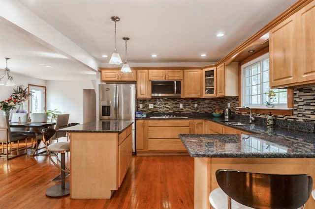 kitchen featuring a kitchen breakfast bar, wood-type flooring, a center island, decorative light fixtures, and sink