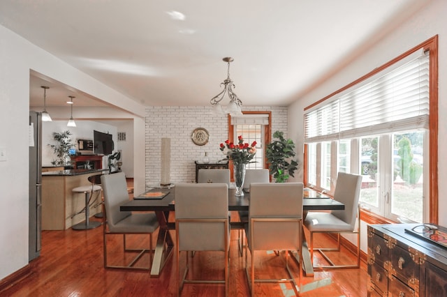 dining room with brick wall, hardwood / wood-style floors, and a wealth of natural light