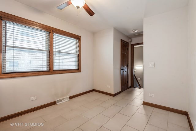 tiled empty room featuring ceiling fan