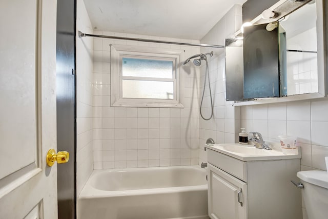 full bathroom with tile walls, vanity, tiled shower / bath, and toilet