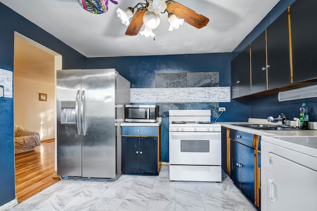 kitchen with washer / clothes dryer, ceiling fan, appliances with stainless steel finishes, light hardwood / wood-style floors, and sink