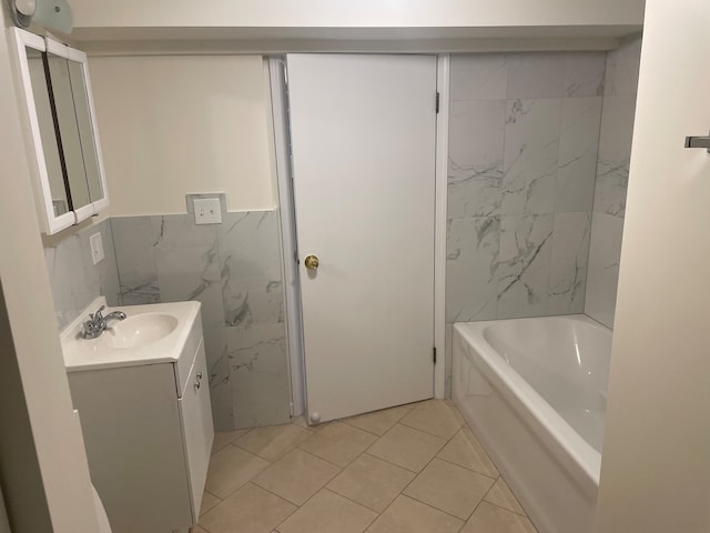 bathroom with tile walls, tile patterned flooring, a bath, and vanity