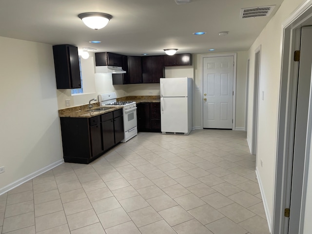 kitchen featuring white appliances, dark brown cabinetry, stone countertops, and light tile patterned floors