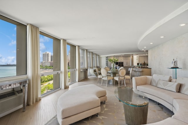 living room with light wood-type flooring, a water view, and expansive windows