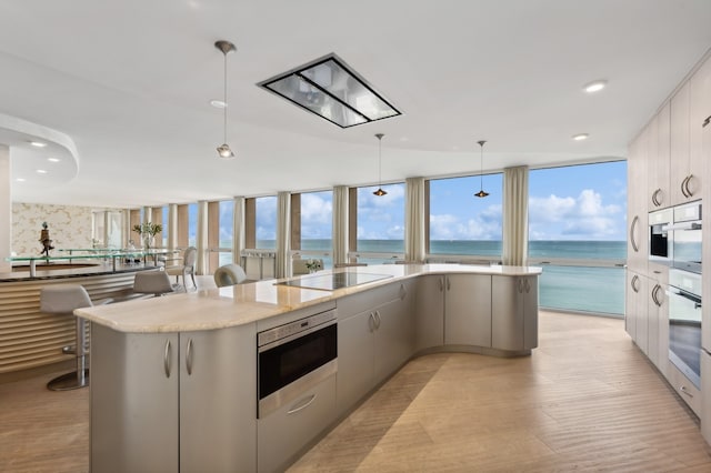 kitchen featuring a water view, appliances with stainless steel finishes, hanging light fixtures, and a kitchen island