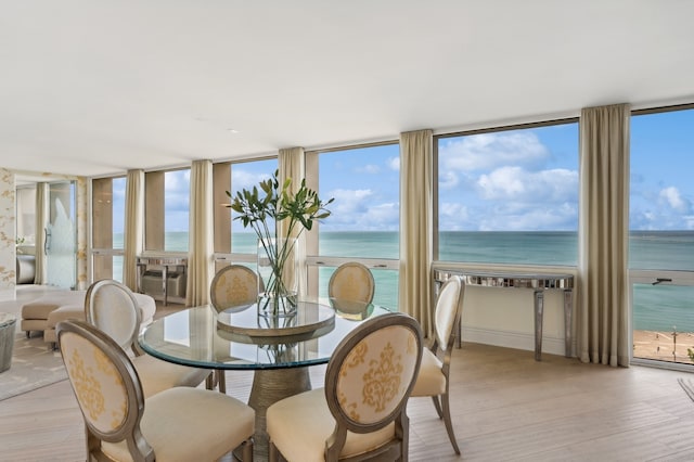 dining space with a water view, light hardwood / wood-style flooring, and expansive windows