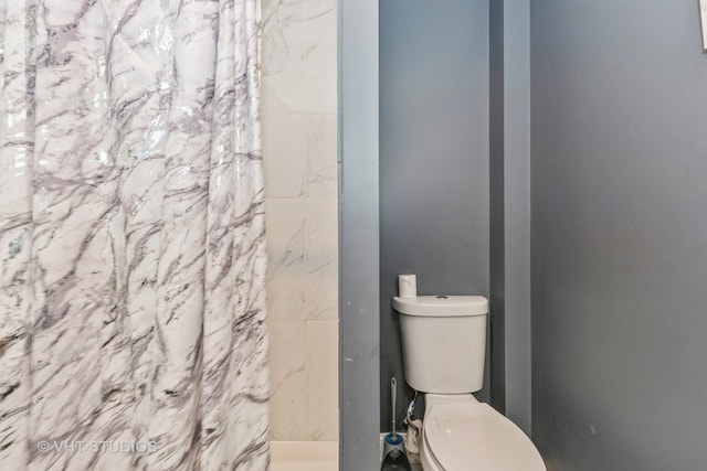 bathroom featuring a shower with curtain and toilet