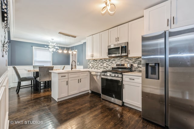 kitchen featuring kitchen peninsula, appliances with stainless steel finishes, white cabinets, and hanging light fixtures