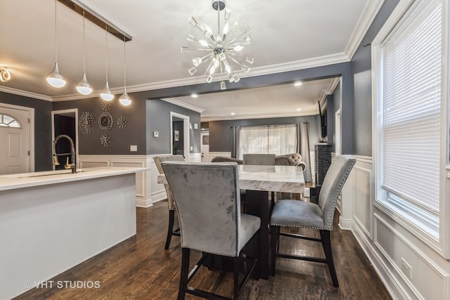 dining room with sink, crown molding, dark wood-type flooring, and an inviting chandelier