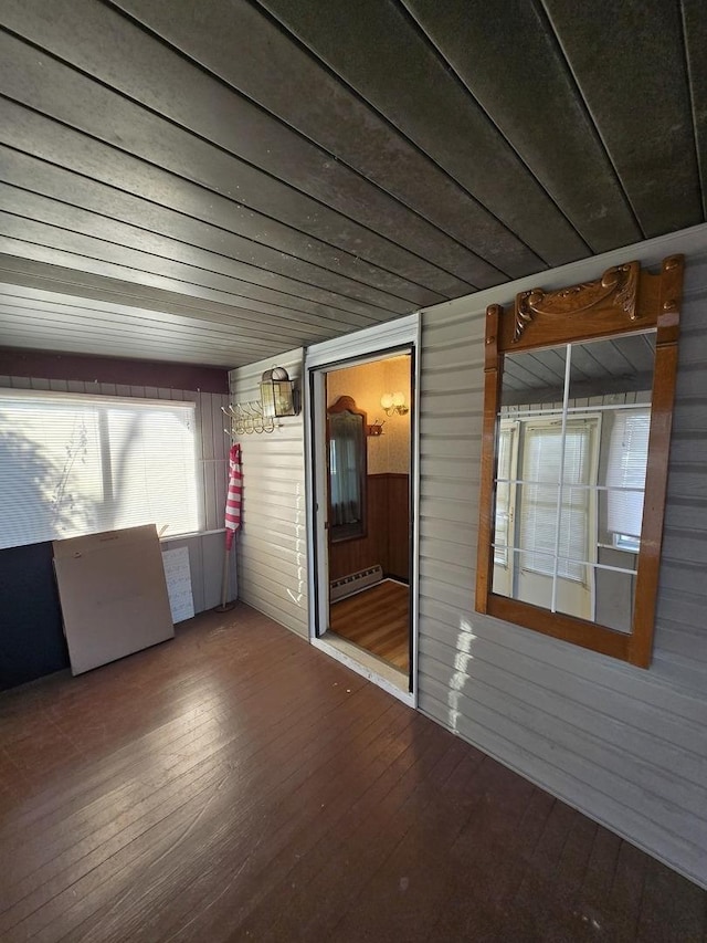 unfurnished room featuring wooden walls, a baseboard radiator, and wood-type flooring